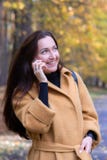 Милая молодая женщина идя в парк осени говоря на падении листьев телефона передвижном ослабляет стоковые фото Милая молодая женщина идя в парк осени говоря на падении листьев телефона передвижном ослабляет стоковые фото