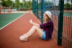 Милая усмехаясь рубашка белокурой девушки нося checkered, белая крышка и шорты джинсовой ткани сидеть положенный на guardlattice стоковое фото Милая усмехаясь рубашка белокурой девушки нося checkered, белая крышка и шорты джинсовой ткани сидеть положенный на guardlattice стоковое фото