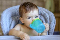 Милый голубоглазый ребёнок держа пластичную кружку в его руках и lookin питьевой воды самой на камере, стоковые фотографии rf Милый голубоглазый ребёнок держа пластичную кружку в его руках и lookin питьевой воды самой на камере, стоковые фотографии rf