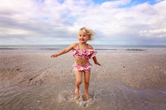 Милый маленький ребенок брызгая и играя в воде на пляже океаном стоковая фотография Милый маленький ребенок брызгая и играя в воде на пляже океаном стоковая фотография