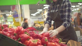 Милый молодой женский работник магазина в коричневой рисберме и белая перчатка на предпосылке покупателей видеоматериал Милый молодой женский работник магазина в коричневой рисберме и белая перчатка на предпосылке покупателей видеоматериал