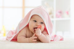 Младенец с teether в рте под купать полотенце на питомнике стоковое фото Младенец с teether в рте под купать полотенце на питомнике стоковое фото