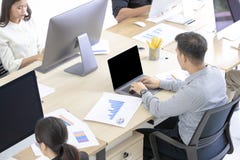 Много азиатских работников умышлены на работе с современными компьютерами стоковая фотография Много азиатских работников умышлены на работе с современными компьютерами стоковая фотография