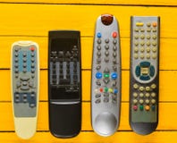 Много устарелых remotes ТВ на желтом деревенском деревянном столе Взгляд сверху стоковое изображение Много устарелых remotes ТВ на желтом деревенском деревянном столе Взгляд сверху стоковое изображение