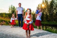 Многодетная семья в этнических украинских костюмах сидит на луге, концепции многодетной семьи стоковые изображения Многодетная семья в этнических украинских костюмах сидит на луге, концепции многодетной семьи стоковые изображения
