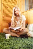 Молодая белокурая женщина сидя на зеленом ковре с книгой стоковые фотографии rf Молодая белокурая женщина сидя на зеленом ковре с книгой стоковые фотографии rf