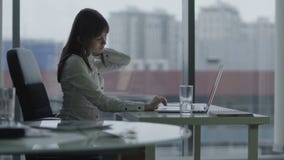 Молодая бизнес-леди работая на компьтер-книжке в современном офисе она останавливает потому что задние повреждения акции видеоматериалы Молодая бизнес-леди работая на компьтер-книжке в современном офисе она останавливает потому что задние повреждения акции видеоматериалы