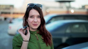 Молодая женщина держа ключи нового автомобиля и усмехаться Молодая женщина держа ключи нового автомобиля и усмехаться