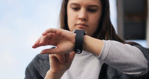 Молодая женщина используя его умный вахту на улице Ветер пошатывает ее волосы Smartwatch, яблоко, время 4k акции видеоматериалы Молодая женщина используя его умный вахту на улице Ветер пошатывает ее волосы Smartwatch, яблоко, время 4k акции видеоматериалы