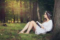 Молодая женщина читая pecefully в красивом лесе стоковое изображение Молодая женщина читая pecefully в красивом лесе стоковое изображение