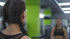 Молодая милая женщина тренирует в спортзале поднимая и понижая гантели перед зеркалом Девушка фитнеса спорта сток-видео Молодая милая женщина тренирует в спортзале поднимая и понижая гантели перед зеркалом Девушка фитнеса спорта сток-видео