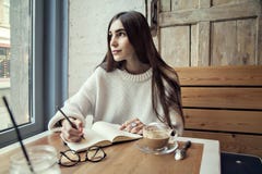 Молодая работа девушки битника в кафе, с блокнотом в кафе около времени обеда окна с кофе стоковое изображение Молодая работа девушки битника в кафе, с блокнотом в кафе около времени обеда окна с кофе стоковое изображение