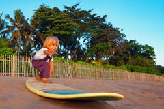 Молодая стойка серфера на surfboard с потехой на пляже захода солнца стоковые изображения Молодая стойка серфера на surfboard с потехой на пляже захода солнца стоковые изображения