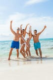 Молодая счастливая потеха havin друзей на пляже стоковое фото rf Молодая счастливая потеха havin друзей на пляже стоковое фото rf