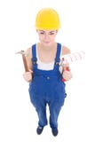 Молодой привлекательный построитель женщины в workwear с молотком и краской Стоковое Изображение Молодой привлекательный построитель женщины в workwear с молотком и краской Стоковое Изображение
