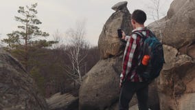 Молодой человек в checkered рубашке стоит на верхней части большого утеса и принимает несколько съемок изумительного пейзажа Отсу акции видеоматериалы Молодой человек в checkered рубашке стоит на верхней части большого утеса и принимает несколько съемок изумительного пейзажа Отсу акции видеоматериалы