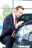 Молодой человек или автоматический торговец в автосалоне Стоковые Изображения Молодой человек или автоматический торговец в автосалоне Стоковые Изображения