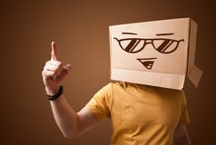 Молодой человек показывать с картонной коробкой на его голове с smiley Стоковое фото RF Молодой человек показывать с картонной коробкой на его голове с smiley Стоковое фото RF
