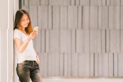 Молодые красивые азиатские девушка или студент колледжа используя smartphone и усмехаться Современный образ жизни, концепция техн стоковое фото Молодые красивые азиатские девушка или студент колледжа используя smartphone и усмехаться Современный образ жизни, концепция техн стоковое фото