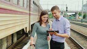 Молодые предприниматели используют таблетку на железнодорожном вокзале Поезд проходит мимо Технология в перемещении акции видеоматериалы Молодые предприниматели используют таблетку на железнодорожном вокзале Поезд проходит мимо Технология в перемещении акции видеоматериалы