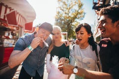 Молодые люди деля candyfloss на ярмарочной площади стоковое изображение Молодые люди деля candyfloss на ярмарочной площади стоковое изображение