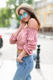 Модно одетая молодая женщина на улице на солнечном вечере Красивая девушка в джинсах, небольшой шляпе и sunglass смотрит стоковое фото Модно одетая молодая женщина на улице на солнечном вечере Красивая девушка в джинсах, небольшой шляпе и sunglass смотрит стоковое фото