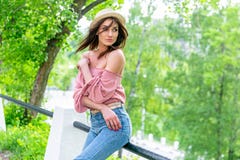 Модно одетая молодая женщина на улице на солнечном вечере Красивая девушка в джинсах и небольшой шляпе стоит и смотрит стоковая фотография Модно одетая молодая женщина на улице на солнечном вечере Красивая девушка в джинсах и небольшой шляпе стоит и смотрит стоковая фотография