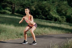 Молодая sporty женщина делая низкие тренировки с круглой резинкой внешней стоковая фотография Молодая sporty женщина делая низкие тренировки с круглой резинкой внешней стоковая фотография