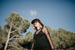 Молодая белокурая женщина идя в природу с черными солнечными очками и одеждами и шляпой Стоковые Фотографии RF Молодая белокурая женщина идя в природу с черными солнечными очками и одеждами и шляпой Стоковые Фотографии RF