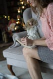 Молодая белокурая женщина сидит на серой софе в розовой блузке и пишет с ее левой рукой с ручкой в тетради рядом с стоковые фотографии rf Молодая белокурая женщина сидит на серой софе в розовой блузке и пишет с ее левой рукой с ручкой в тетради рядом с стоковые фотографии rf