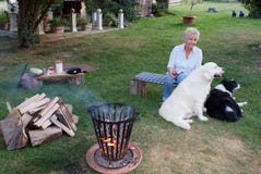 Молодая белокурая женщина сидит с ее золотым Retriever и Коллиой границы лагерным костером стоковая фотография rf Молодая белокурая женщина сидит с ее золотым Retriever и Коллиой границы лагерным костером стоковая фотография rf