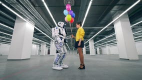 Молодая женщина gifting воздушные шары к высокорослому роботу сток-видео Молодая женщина gifting воздушные шары к высокорослому роботу сток-видео