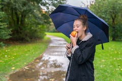 Молодая женщина Smilling есть яблоко на открытом воздухе стоковая фотография Молодая женщина Smilling есть яблоко на открытом воздухе стоковая фотография