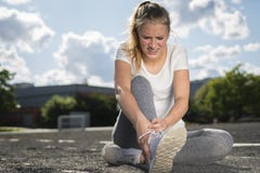 Молодая женщина в sportswear раненом ее лодыжка пока делать резвится стоковое фото Молодая женщина в sportswear раненом ее лодыжка пока делать резвится стоковое фото