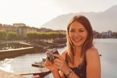 Молодая женщина используя винтажную камеру перед прогулкой озера в Ascona стоковое изображение rf Молодая женщина используя винтажную камеру перед прогулкой озера в Ascona стоковое изображение rf