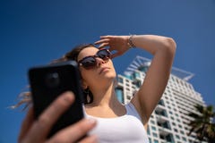 Молодая женщина используя телефон Горизонт города в предпосылке стоковая фотография Молодая женщина используя телефон Горизонт города в предпосылке стоковая фотография