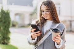 Молодая женщина отправляя SMS или используя смартфону стоковая фотография Молодая женщина отправляя SMS или используя смартфону стоковая фотография