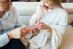 Молодая женщина получая коробку подарка сюрприза красную от ее парня на софе стоковые изображения Молодая женщина получая коробку подарка сюрприза красную от ее парня на софе стоковые изображения