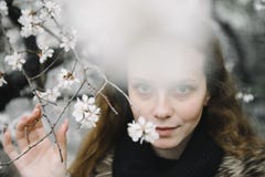 Молодая женщина представляя на улице против цветя дерева стоковая фотография rf Молодая женщина представляя на улице против цветя дерева стоковая фотография rf