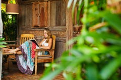 Молодая женщина прочитала бумажную книгу на внешней веранде Стоковые Фотографии RF Молодая женщина прочитала бумажную книгу на внешней веранде Стоковые Фотографии RF