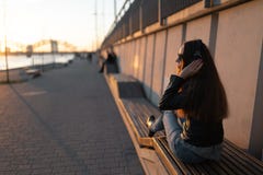 Молодая женщина слушает музыку в закрытых наушниках через ее телефон стоковое изображение Молодая женщина слушает музыку в закрытых наушниках через ее телефон стоковое изображение