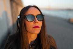 Молодая женщина слушает музыку в закрытых наушниках через ее телефон стоковые фотографии rf Молодая женщина слушает музыку в закрытых наушниках через ее телефон стоковые фотографии rf