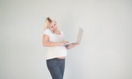 Молодая красивая беременная женщина работая на ноутбуке Беременная бизнес-леди ища информацию и онлайн покупки дальше стоковое изображение rf Молодая красивая беременная женщина работая на ноутбуке Беременная бизнес-леди ища информацию и онлайн покупки дальше стоковое изображение rf