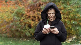 Молодая красивая девушка используя смартфон в парке осени стоковые изображения rf Молодая красивая девушка используя смартфон в парке осени стоковые изображения rf