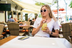 Молодая красивая женщина в круглых солнечных очках с коктейлем на террасе кафа имея потеху стоковые фото Молодая красивая женщина в круглых солнечных очках с коктейлем на террасе кафа имея потеху стоковые фото