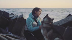 Молодая красивая женщина идя с сибирской сиплой собакой на пляже на заходе солнца, замедленном движении акции видеоматериалы Молодая красивая женщина идя с сибирской сиплой собакой на пляже на заходе солнца, замедленном движении акции видеоматериалы