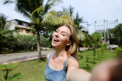 Молодая милая девушка звоня видео- smartphone около пальм в предпосылке стоковое фото rf Молодая милая девушка звоня видео- smartphone около пальм в предпосылке стоковое фото rf