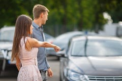 Молодая пара выбирает их первый автомобиль Любовники идут вокруг каравана и смотрят автомобили Q стоковое фото rf Молодая пара выбирает их первый автомобиль Любовники идут вокруг каравана и смотрят автомобили Q стоковое фото rf
