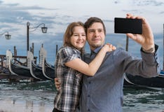 Молодая пара принимает selfie с smartphone в Венеции в Италии Гондолы в предпосылке стоковое фото rf Молодая пара принимает selfie с smartphone в Венеции в Италии Гондолы в предпосылке стоковое фото rf