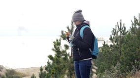 Молодая туристская девушка, стоя на высоком банке озера, смотрит что-то в телефоне slowmotion, HD, 1920x1080 видеоматериал Молодая туристская девушка, стоя на высоком банке озера, смотрит что-то в телефоне slowmotion, HD, 1920x1080 видеоматериал